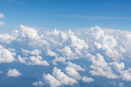White, puffy clouds against a blue sky from an airplane