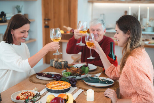 Adult daughter celebrates Christmas and New Year dinner with her parents at home. Concept of family reunion, holiday meal, homecoming, festive celebration, and togetherness.