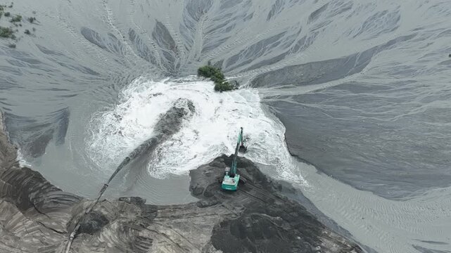 Aerial view of an excavator working at a sediment discharge site in Kali Baru, Cilincing, Jakarta, Indonesia.
