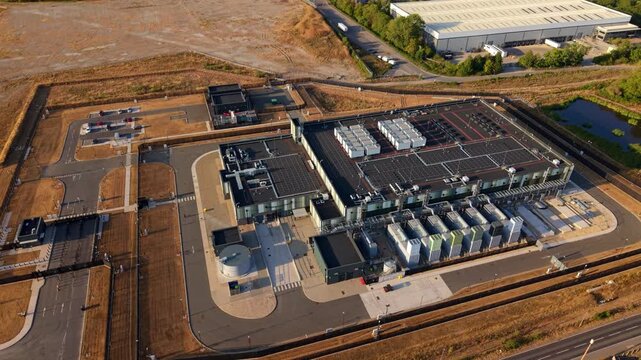 Aerial view of a modern hyperscale data center featuring rows of cooling units on the roof and surrounding infrastructure in Didcot, England, United Kingdom.