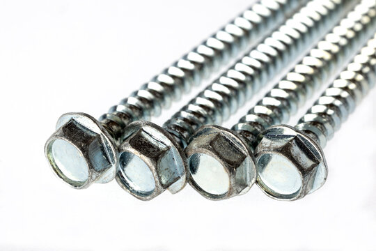 Close-up of metal hex bolts. The bolts are shiny and have a threaded stem, located on a white background.