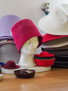 A red hat and other small colorful hats with a mannequin head.