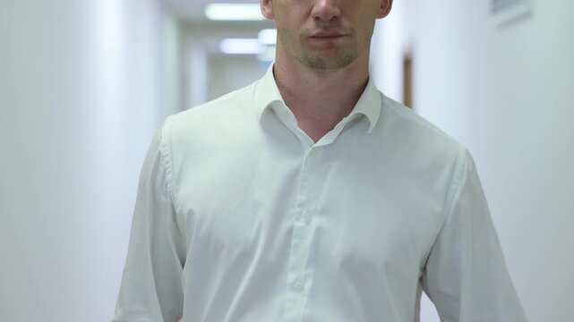 Successful male executive in a formal suit walking through a bright corporate hallway directly towards the camera.Split screen or sequence of a professional businessman walking back and forth in a con