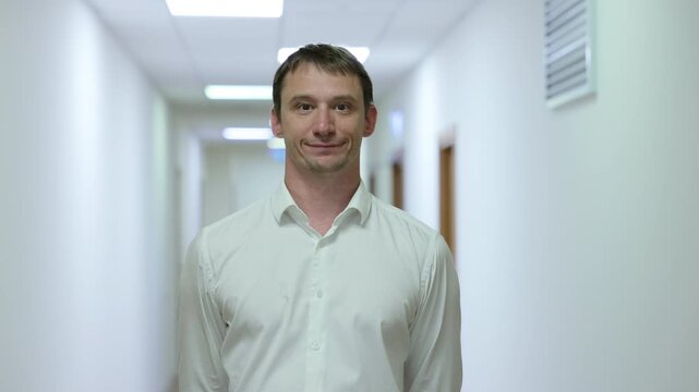 Successful male executive in a formal suit walking through a bright corporate hallway directly towards the camera.Split screen or sequence of a professional businessman walking back and forth in a con
