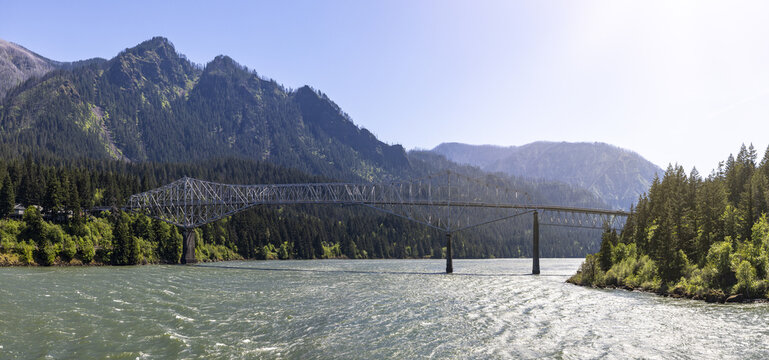 View of the Bridge of the Gods spanning the Columbia River, framed by lush forested mountains and flowing water in Cascade Locks, Oregon, United States.