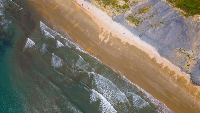 Aerial view of the sandy beach and dramatic cliffs along the Jurassic Coast in Lyme Regis, England, United Kingdom.