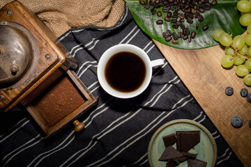 White mug with dark coffee, wooden grinder and green beans on table © Kristof