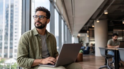 Fototapeta premium Thoughtful man looking out window while working on laptop