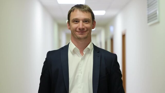 Successful male executive in a formal suit walking through a bright corporate hallway directly towards the camera.Split screen or sequence of a professional businessman walking back and forth in a con