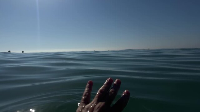 Woman touching seawater with hand. Swimming woman closeup. 4k