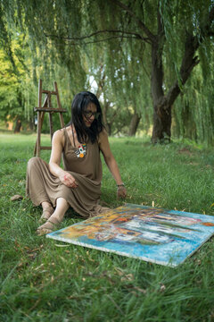 Portrait of an attractive woman artist painter sitting on the grass outdoors
