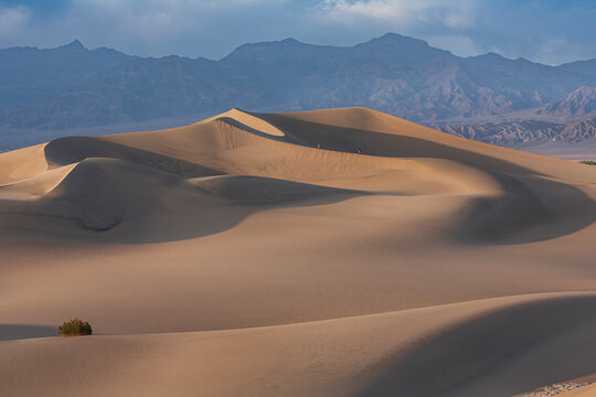 Beautiful wide panorama of sand dunes with tiny hikers on a ridge in Death Valley