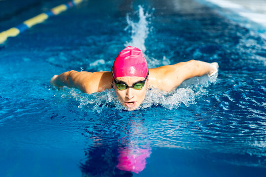 Female swimmer performing butterfly stroke in pool, concept of sport discipline