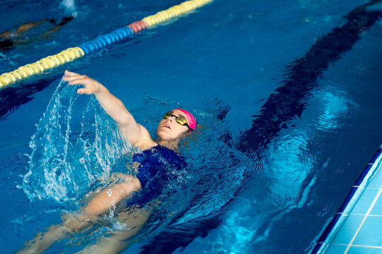 Female swimmer training backstroke, showing discipline and self-improvement in pool