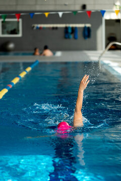 Female swimmer pushing through water, developing strength and fitness during rigorous training