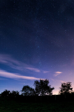 Night landscape showing starry sky and clouds over illuminated villages of Karrantza valley in Bizkaia Basque Country Spain