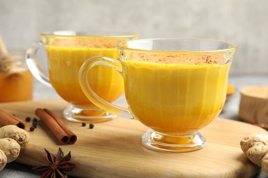 Golden milk turmeric latte and ingredients on grey table, closeup