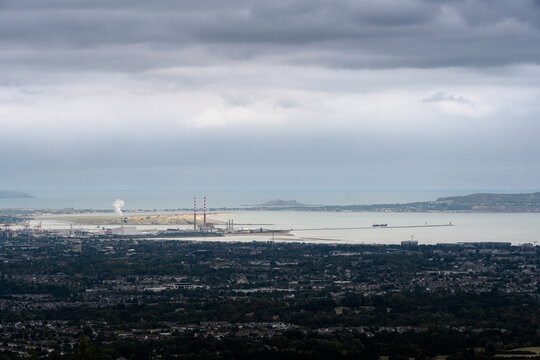 Elevated panoramic cityscape view of Dublin city, Dublin Bay, Poolbeg power station chimneys, and Howth peninsula in Ireland