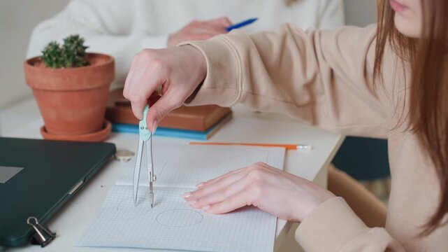Caucasian student practicing geometry at desk, using compass on graph paper, steady hands and pencil, notebook and binder beside, small potted succulent and closed laptop, soft natural light,