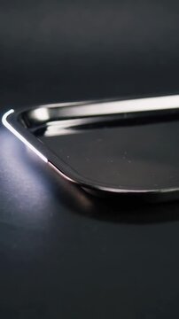 Vertical video: Sweeping offframe LED across steel tray in studio camera revealing rim and dust