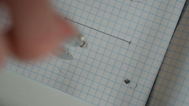 Closeup hand erasing pencil line, tutor guiding student during focused home study on graph paper with faint grid and small dot, gentle coaching atmosphere, manicured nail visible, subtle smudge