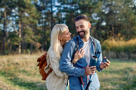 Hiking couple  enjoys nature  taking a break with water bottle  in a lush forest during a sunny day