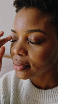 Vertical video: Lifting right hand as woman rubbing eye on bed, soothing with fingers, in sweater