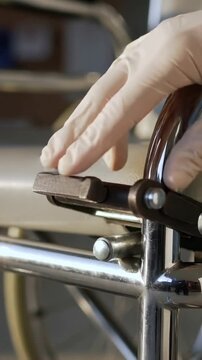Vertical video: Hovering gloved hand pressing latch on armrest at clinic, releasing, copy space