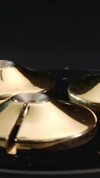 Vertical video: Camera shifting revealing three gold disks on studio base exposing silver caps slit