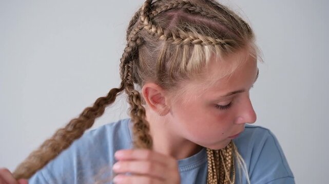The girl is unbraiding her braids. Her hair has become curly.