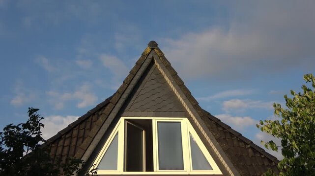 Dormer window on house roof with moving clouds