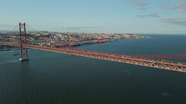 Wide aerial view of the 25 de Abril suspension bridge crossing the Tagus River toward the Lisbon waterfront