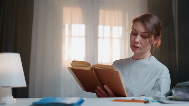 Caucasian woman tutor reading book by lamp, cozy home study with window light, annotating grammar notes, focused expression, neat desk with notebook and pen, warm morning atmosphere