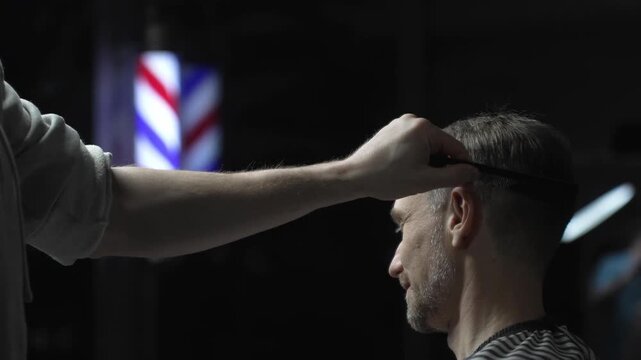 Professional barber carefully checking customer's hair texture and head contours, preparing for precise haircut, vintage barbershop interior with iconic striped pole visible