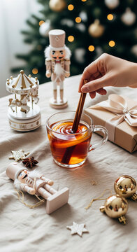 Vertical View of Hand Stirring Cinnamon Tea with Wooden Nutcracker and Wrapped Gift for Winter Social Media Stories