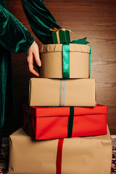 Hand arrange wrapped holiday gift stack with green ribbon