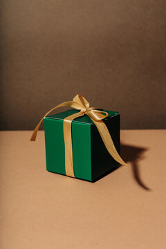 Green gift box with gold ribbon and bow