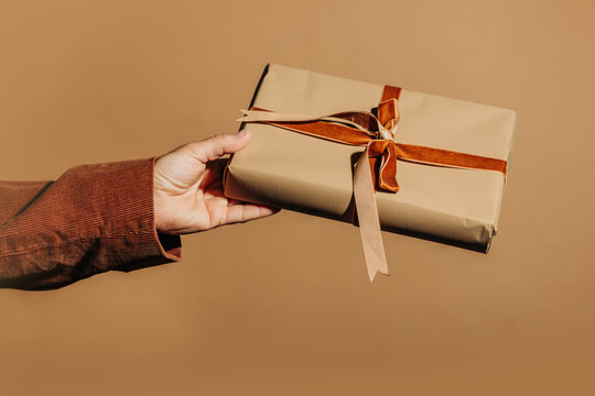 Hand holding wrapped gift with ribbon for Holiday celebration