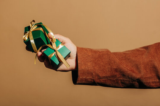 Hand hold green gift box with gold ribbon for Holiday