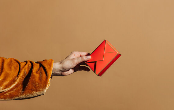 Hand hold red envelope gift against bright beige background