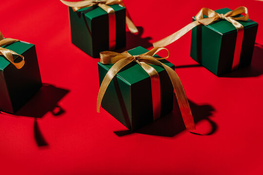 Green gift box with gold ribbon on bright red background