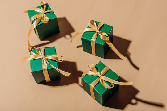 Green gift box with gold ribbon on beige background
