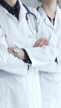Doctors from a medical team are standing with arms crossed, wearing white coats and stethoscopes, representing unity, success, and trust in a healthcare environment