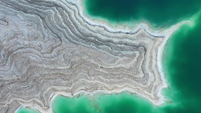 Aerial view of the Dead Sea sinkholes and salt formations along the turquoise shoreline in Beersheba, South District, Israel.