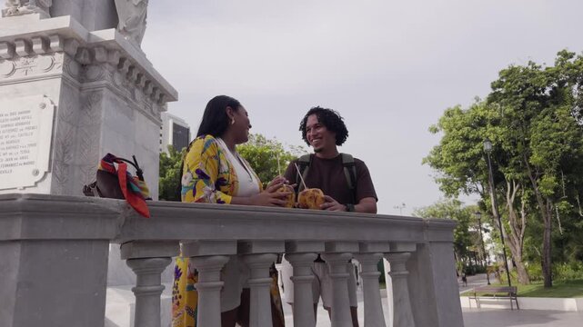 Happy latin couple enjoying coconuts in a park
