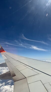 Vista da asa de avi&atilde;o durante voo acima das nuvens sob c&eacute;u azul 2026