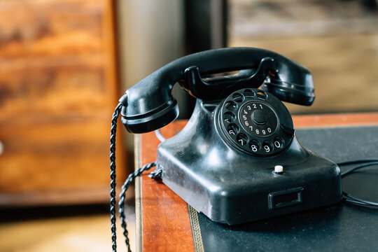 Vintage black rotary telephone on antique wooden desk