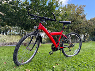 Fototapeta premium Red Mountain Bicycle Parked on Green Grass Lawn in Public Park