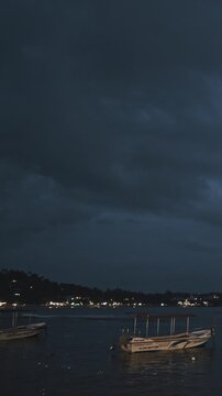 Boats resting on the shore under a dramatic twilight sky