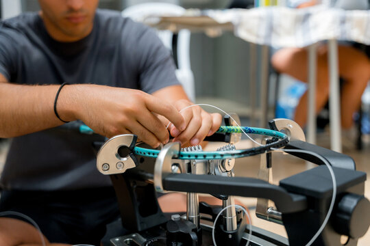 Man repair badminton racket with stringing machine